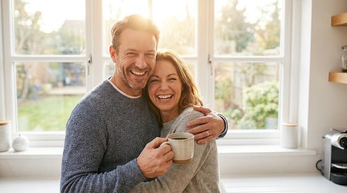 Pareja sonriendo y abrazándose en su cocina